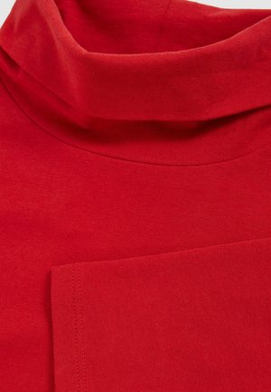 Top de cuello alto rojo con una textura suave. Presenta un cuello doblado y un pequeño bolsillo en la parte frontal, cosido con hilo a juego.