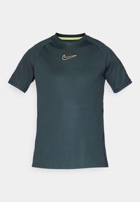 Tumši tējas krāsas sporta krekls ar īsām piedurknēm, apaļu kakla izgriezumu un dzeltenu Nike logotipu uz krūtīm. Izgatavots no gludas, vieglas auduma.