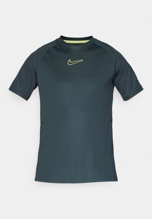 Tumši tējas krāsas sporta krekls ar īsām piedurknēm, apaļu kakla izgriezumu un dzeltenu Nike logotipu uz krūtīm. Izgatavots no gludas, vieglas auduma.