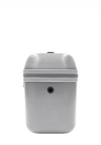 Zaino rigido grigio con superficie texturizzata, chiusura con zip e un foro di ventilazione circolare sulla parte frontale. Design con parte superiore arrotondata.