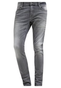 Vaqueros de mezclilla gris descoloridos con un corte ajustado, diseño de cinco bolsillos y sutiles detalles de desgaste. Fabricados con una tela suave y texturizada de mezcla de algodón.