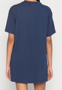 Granatowa bawełniana koszulka, luźny krój, krótkie rękawy, okrągły dekolt, gładka tekstura, sięgająca powyżej połowy uda, minimalne detale szwów.