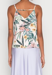 Débardeur imprimé floral avec un dos en V, des bretelles fines et un tissu léger aux motifs roses et verts sur un fond clair.