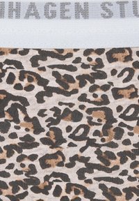 Leren stof met luipaardprint en een elastische witte tailleband met daarop vage grijze tekst aan de bovenrand.