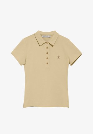 Camiseta polo beige con cuello, mangas cortas, seis botones marrones y una pequeña figura bordada en marrón en el lado izquierdo del pecho. Textura de tela suave.