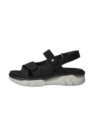 Zwarte suede sandaal met een open te ontwerp, verstelbare band en een witte rubberen zool met een geribbeld patroon.