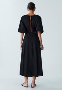 Must rüüstmidi kleit lühikeste lõhnavate varrukatega, avatud seljaosaga ja nöörkinnitusega, põrandapikkusega. Sile kangas vähese tekstuuriga.