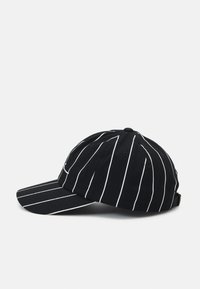 Fekete baseball sapka függőleges fehér csíkokkal, pamutból készült. Ívelt napellenzővel és hátsó állítható pánttal rendelkezik.