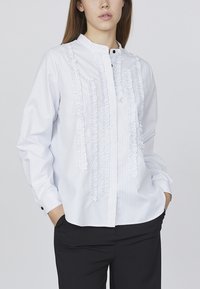 Hvid, stribet bluse med flæsefrontdetalje, knaplukning, båndkrave og lange ærmer. Stof ser glat og let ud.