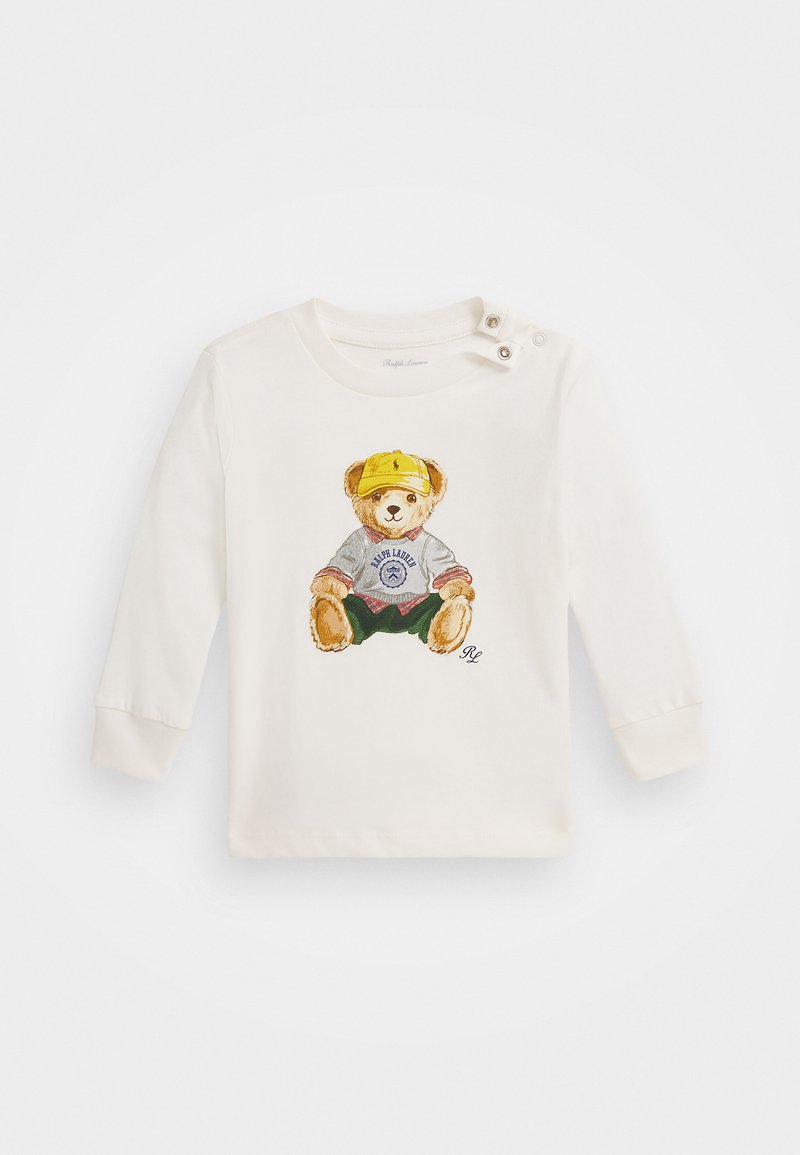 Hosszú ujjú krémszínű pamut ing, sárga sapkás, szürke pulóveres és zöld sortos medve grafikával; gombos díszek a vállon.