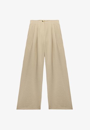 Beżowe spodnie szerokie z teksturowanej tkaniny, z plisami z przodu i zapięciem na guzik w talii. Prosta sylwetka, bez kieszeni.