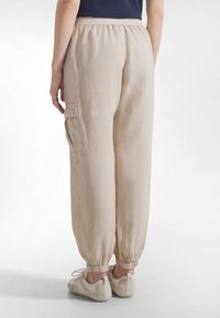 Beiget pellavahousut, joissa on joustava vyötärönauha, kapenevat lahkeet ja sivussa oleva tasku, kevyen tekstuurin ja rento istuvuus.