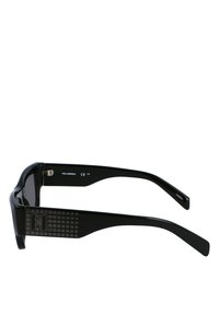 Occhiali da sole neri con lenti rettangolari, montatura spessa, astine nere texturizzate con motivo a griglia e un sottile dettaglio del logo sul lato.