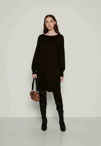 Μαύρο φόρεμα-πουλόβερ με μακριά μανίκια, ίσια γραμμή, συνδυασμένο με μαύρες μπότες μέχρι το μηρό και μια μικρή τσάντα με λεοπάρ σχέδιο. Λείος υφασμάτινος ιστός.