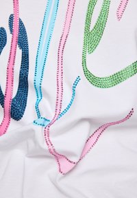 White fabric with colorful rhinestone patterns in blue, green, pink, and purple, featuring wavy lines and varying thicknesses.