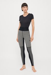 Svart topp med rund halsringning, parat med randiga och mönstrade svarta leggings som har varierande texturer och hög midja.