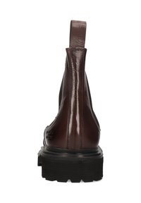 Botín de cuero marrón, acabado suave, paneles laterales elásticos, tira en el talón, suela de goma negra con superficie texturizada, branding minimalista.