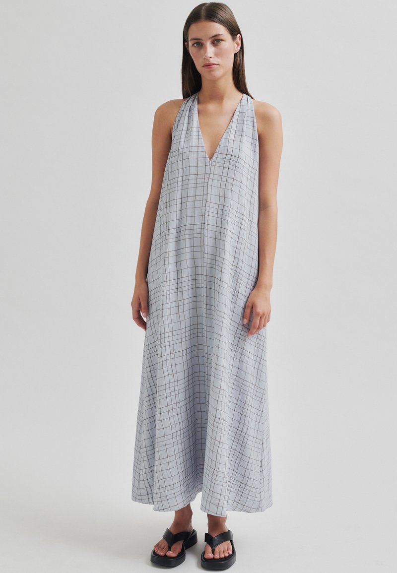Rochie lungă, gri, cu bretele halter și decolteu adânc în V, cu un model în carouri. Fabricată dintr-un material ușor, având o siluetă fluidă și fente laterale.