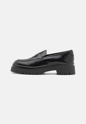 Black patent leather loafers with a rounded toe, a low chunky rubber sole, and decorative stitching across the front. Simple design with minimal accents.