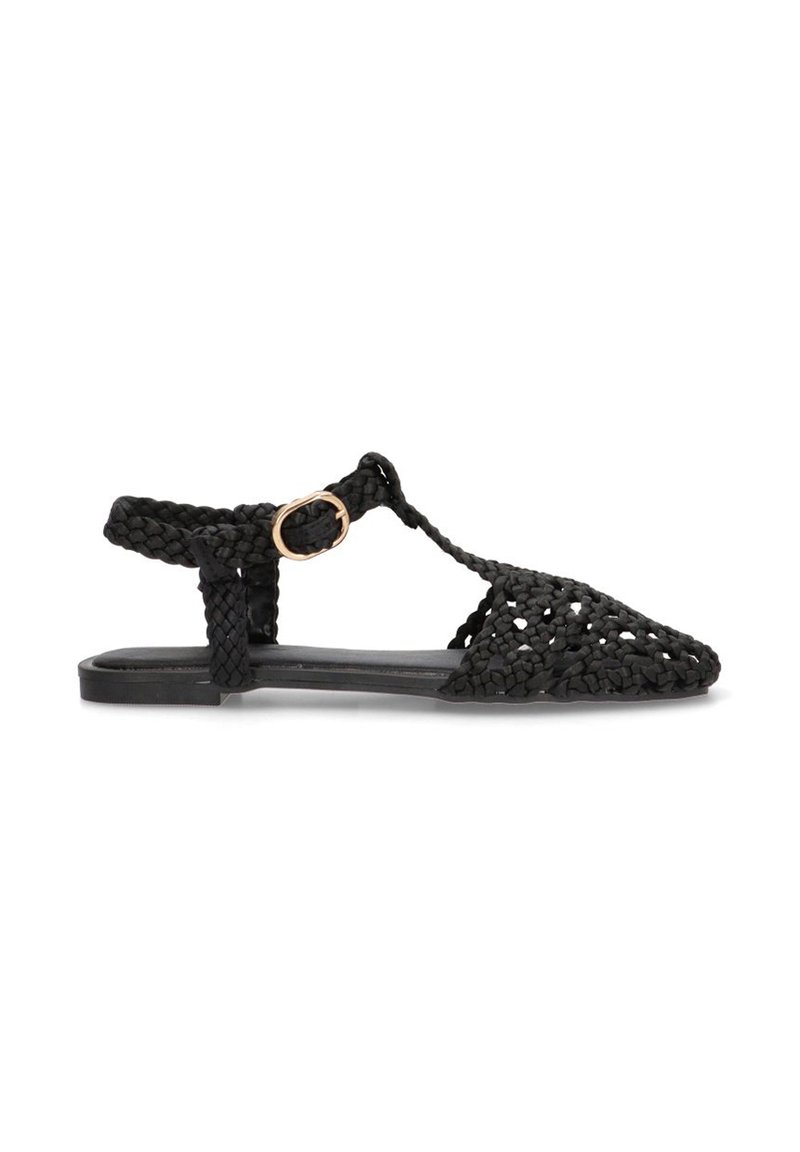 Sandalia negra de tejido con diseño de punta, que presenta un upper texturizado, correa ajustable en el tobillo y una suela plana con un hardware mínimo.