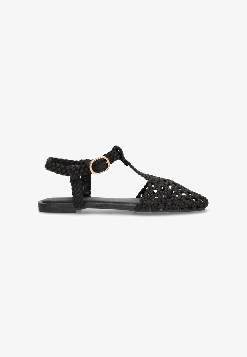 Sandalia negra de tejido con diseño de punta, que presenta un upper texturizado, correa ajustable en el tobillo y una suela plana con un hardware mínimo.