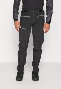 Pantalons de plein air pour hommes en gris foncé, dotés de poches zippées, d'une taille ajustable et d'un mélange de tissu lisse et texturé.