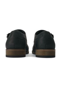 Black leather shoes with a flat heel featuring a wooden accent. The design includes a simple buckle detail and rounded edges.