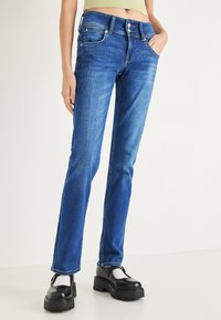 Modre jeans hlače iz jeansa s krojem ravnih nogavic. Imajo visok pas, sprednje žepe in srebrne gumbe, ki ustvarjajo gladko teksturo.