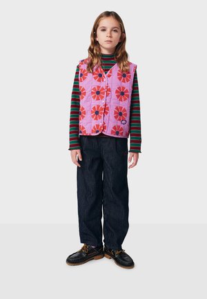 Quilted pink vest with red floral pattern over a striped green and black long-sleeve shirt, paired with dark striped pants and black shoes.