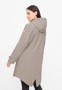 Lichtbeige waterdichte jas met capuchon, voorzien van lange mouwen, drukknoopsluiting en een rugventilatie voor meer bewegingsvrijheid. Gladde, matte textuur.