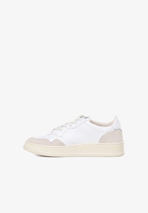 Zapatillas de cuero blancas con acentos de ante beige. Punta redondeada, diseño plano con cordones y suela de goma texturizada. Etiqueta visible en el talón.