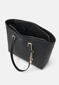 Sac fourre-tout noir en matériau texturé avec quincaillerie dorée, fermeture à glissière et poches intérieures ; comprend un charme décoratif.