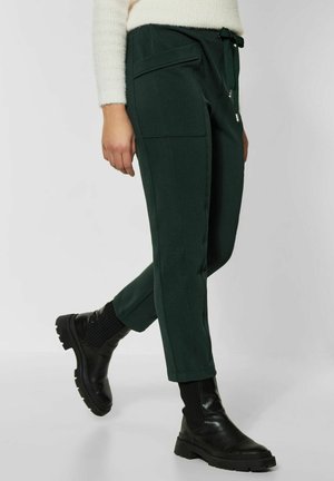 Pantalones verdes, ajustados, hechos de un tejido texturizado con una cintura elástica y cordón, que cuentan con dos bolsillos laterales y puños acampanados.