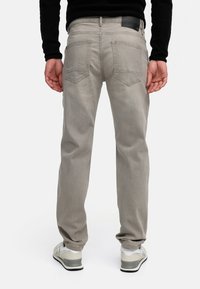Light gray jeans with a straight cut, two back pockets, and a black label on the waistband, paired with light sneakers.