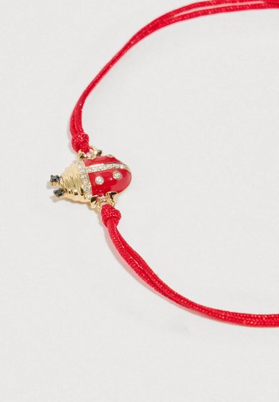 Sarkans virtenes rokassprādze ar zelta un sarkana mārītes piekariņu, rotātu ar mazām caurspīdīgām un melnām dārgakmeņiem uz balta fona.