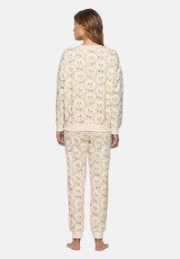 Conjunto de loungewear color crema con un diseño estampado de caras de osos; incluye una camiseta de ajuste relajado y pantalones a juego con puños.