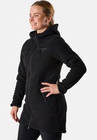 Schwarze Fleecejacke mit Kapuze, Reißverschluss vorne und Seitentaschen. Sie verfügt über eine weiche, strukturierte Oberfläche und eine verstellbare Schnürung an der Kapuze.