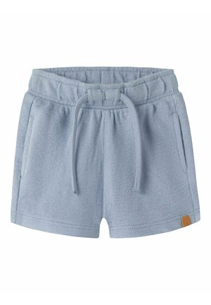Short en éponge bleu clair avec taille élastique, cordon, poches latérales et petite étiquette marron sur l'ourlet.