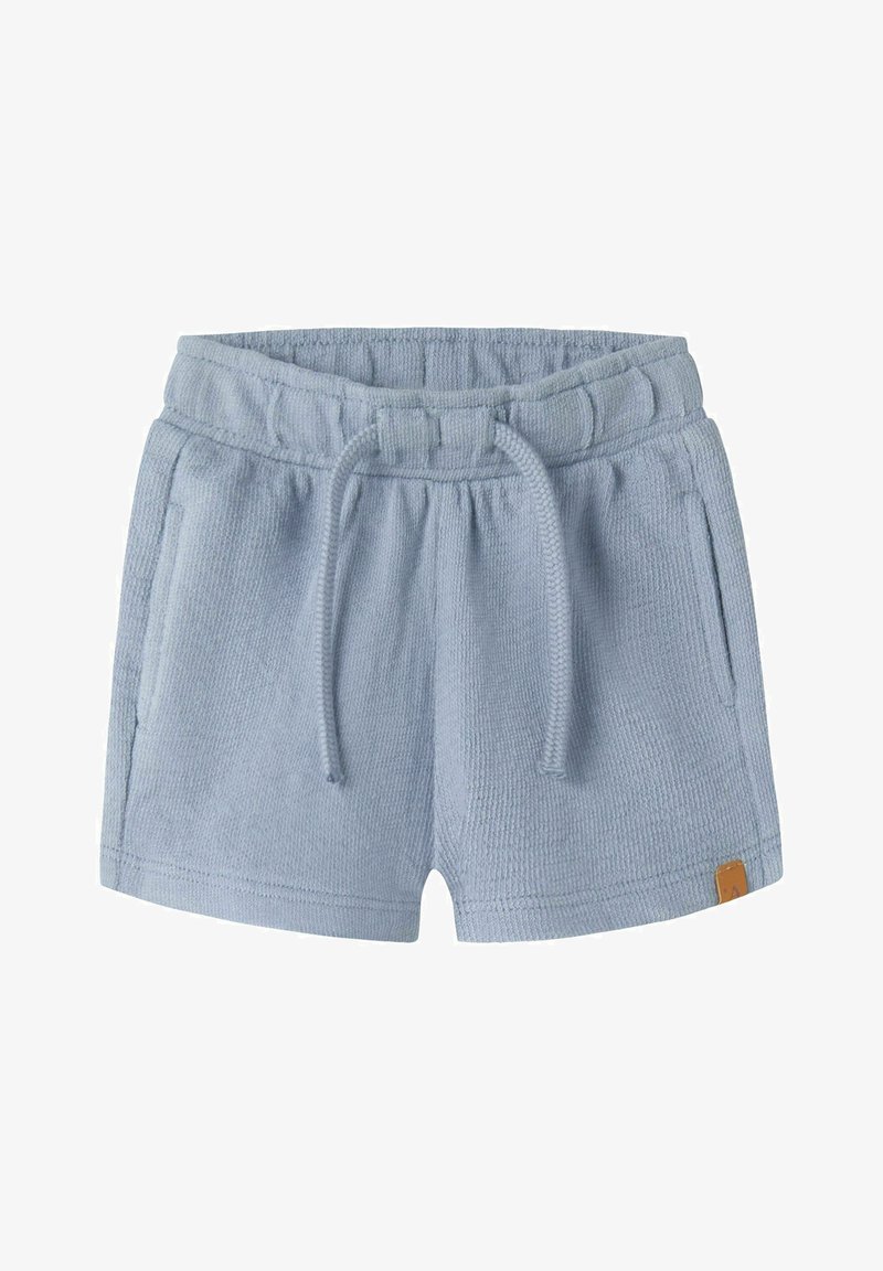 Short en éponge bleu clair avec taille élastique, cordon, poches latérales et petite étiquette marron sur l'ourlet.