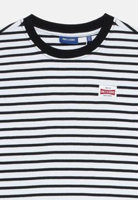 Svart-hvitt stripet kortermet t-skjorte med svart ribbestrikket krage og en liten rød og hvit etikett på venstre side.