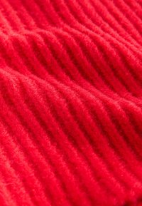 Tessuto a maglia rosso a coste, caratterizzato da un motivo testurizzato con sezioni alternate rialzate e piatte, realizzato in materiale morbido e soffice.