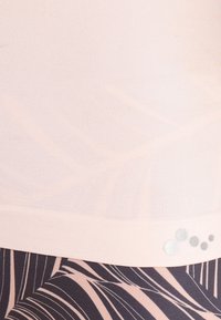 Ljusrosa atletisk topp tillverkad av ett slätt material, med ett subtilt bladmönster och en silverpunkt som accent vid fållen.