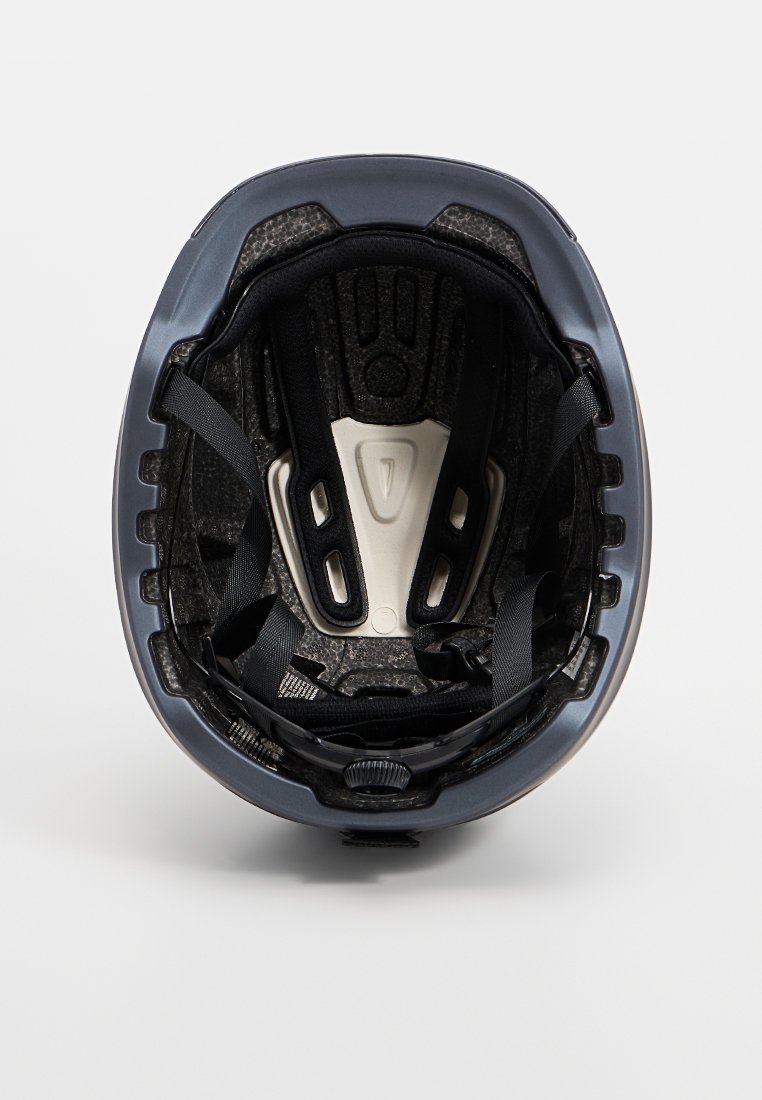 Cyklistická helma s lesklým námořnickým exteriérem, vnitřním polstrováním, černými popruhy a nastavitelným systémem. Obsahuje ventilační otvory pro průtok vzduchu.