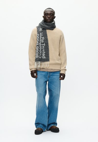 Beežist kootud sviiter, helesinised flared teksad, hall sall valgete tähtedega, friteeritud servadega ja tumedad jalatsid. Lihtne ja mugav disain.