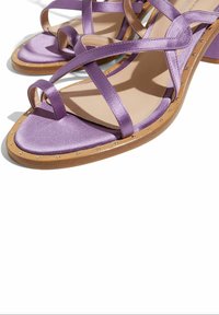 Ljubičaste satenske sandale s ukriženim trakama, niskim blokanom petom i noktima duž đona. Glatka tekstura s dizajnom zaobljenog vrha.