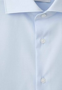 Jasnoniebieska koszula z długim rękawem, posiadająca kołnierzyk typu włoskiego, zapięcie na przodzie na białe guziki oraz gładką, jednolitą fakturę tkaniny.