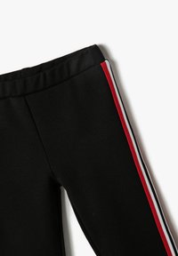 Leggings negros con una textura suave, cinturilla elástica y rayas verticales en rojo, blanco y gris a lo largo de las costuras laterales.