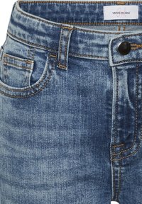Denimjeans i medelblå färg med blekta detaljer. Femficksdesign, kopparstickningar och knappstängning. Vero Moda-logotyp på midjan.