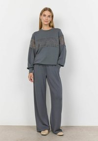 Conjunto de loungewear gris que incluye una camiseta de manga larga con detalles de encaje y pantalones de pierna ancha, confeccionado en una tela suave con una textura lisa.
