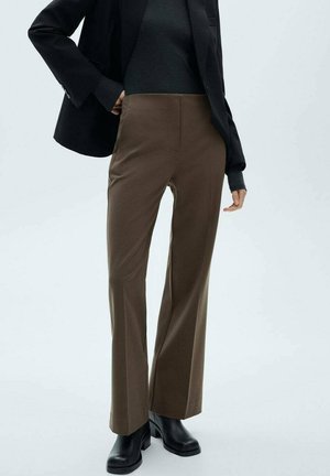 Bruine op maat gemaakte broek van gestructureerde stof, met een hoge taille en een rechte pijp, gecombineerd met een zwarte blazer en laarzen.